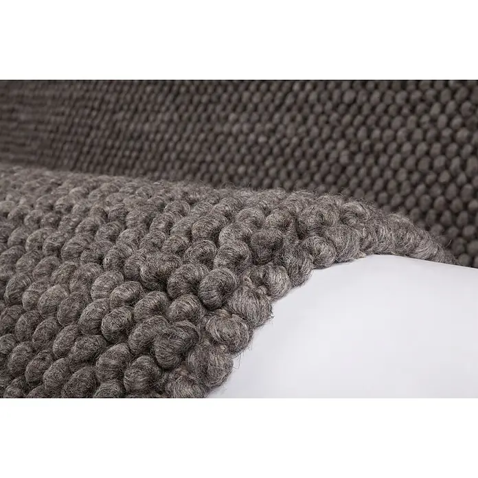 Kayoom Wollteppich Attic 590 - Graphit, 230 x 160 cm, 50 % Wolle, 50 % Viskose - Nahaufnahme eines dunkelgrauen, strukturierten Wollteppichs mit markantem Schleifen- oder Noppendesign.