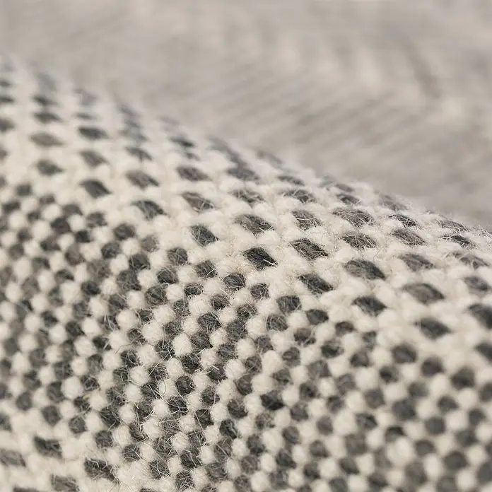 Kayoom Wollteppich Bombay 343 - Silber, 200 x 140 cm, 100 % Wolle - Nahaufnahme eines strukturierten, gebrochen weißen und dunkelgrauen Teppichs mit Schachbrettmuster.