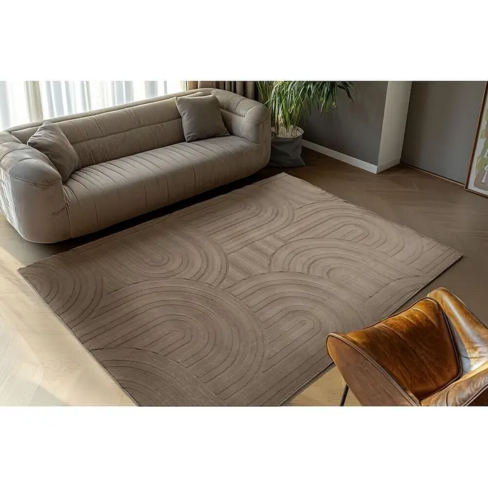 Kayoom Kurzflorteppich Cosmic 526 - Taupe, 230 x 160 cm, 85 % Polyester, 15 % Wolle - Beiger/taupefarbener Teppich mit geprägten Kreismustern auf Holzfußboden in einem Wohnzimmer.