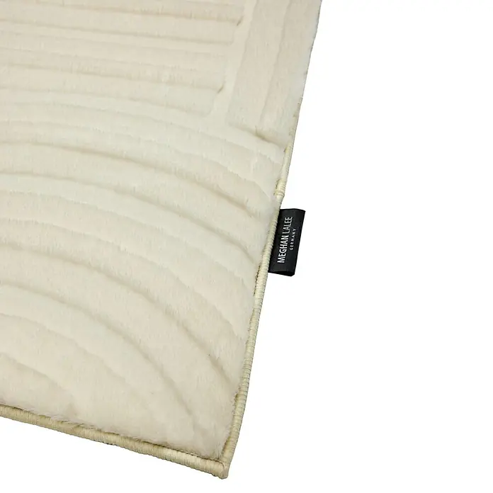 Kayoom Kurzflorteppich Cosmic 526 - Weiß, 230 x 160 cm, 85 % Polyester, 15 % Wolle - Hellcremefarbene strukturierte Matte mit Rippenmuster und schwarzem Markenetikett 'MEGHAN LALEE GERMANY'.