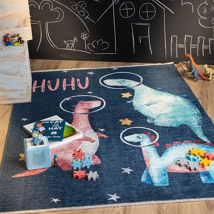 Kayoom Kinderteppich Joanna 627 - Multi, 170 x 115 cm, 70 % Baumwolle, 30 % Polyester - Blauer Kinderteppich mit Weltraumdinosauriern, Sternen und 'HUHU'-Text, in einem verspielten Raum mit Spielzeug und Büchern.