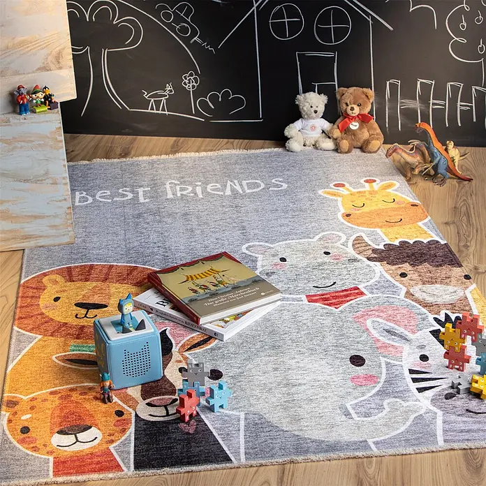 Kayoom Kinderteppich Joanna 616 - Multi, 170 x 115 cm, 70 % Baumwolle, 30 % Polyester - Ein farbenfroher grauer Kinderteppich mit Tiergesichtern und „BEST FRIENDS“-Schriftzug, umgeben von Spielzeug und Büchern im Spielzimmer.