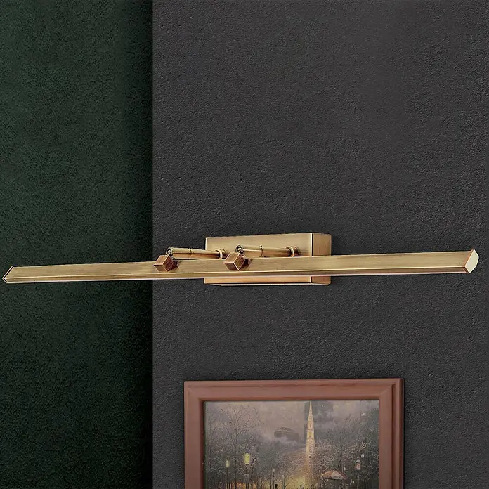 Orion Leuchten Wandleuchte - 15 W, L x B x H: 14,5 x 75 x 6 cm - Goldene Messing-Bilderleuchte an dunkler Wand, die ein gerahmtes Gemälde darunter beleuchtet.
