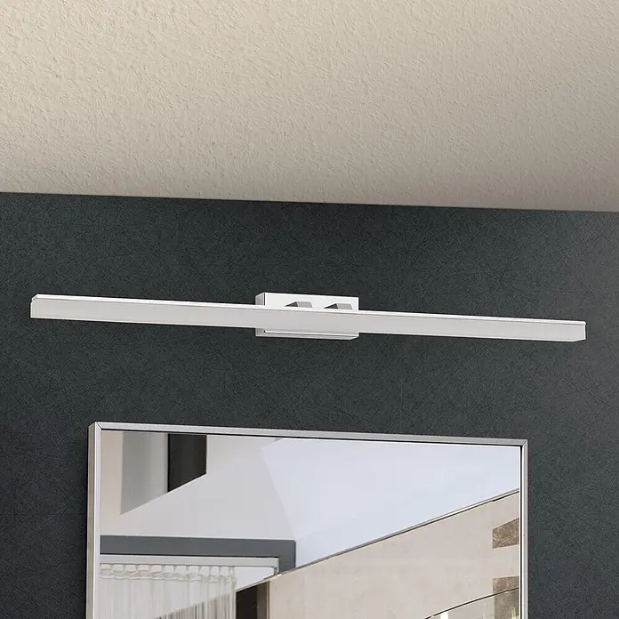 Orion Leuchten Wandleuchte - 15 W, L x B x H: 10 x 75 x 5 cm - Eine schlanke, lineare silberne LED-Spiegelleuchte beleuchtet eine dunkle Strukturwand über einem Spiegel.