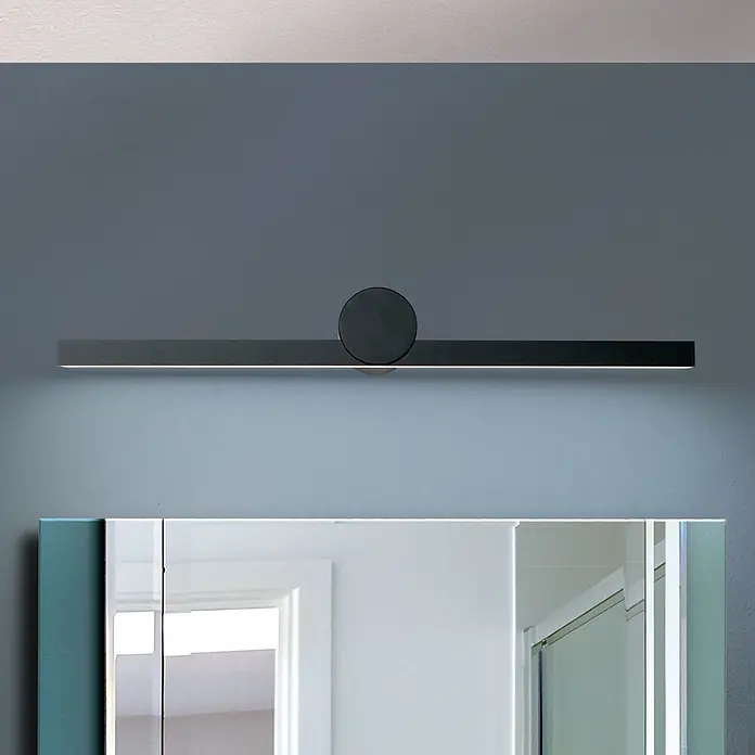 Orion Leuchten Wandleuchte - 12 W, L x B x H: 10 x 61 x 7,6 cm - Schwarze, rechteckige LED-Spiegelleuchte mit zentralem Rundelement, über einem Spiegel montiert.