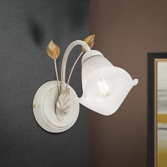 Orion Leuchten Wandleuchte - 40 W, L x B x H: 26 x 14 x 22,5 cm, E14 - Eine weiß patinierte Wandleuchte mit dekorativen goldfarbenen Blättern und einem weißen Glasschirm, an einer strukturierten Wand montiert.