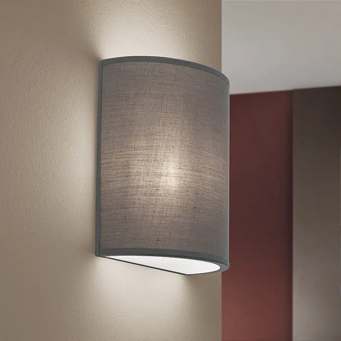 Orion Leuchten Wandleuchte - 9 W, L x B x H: 10 x 18 x 22 cm, E14 - Graue Stoff-Halbzylinder-Wandleuchte, beleuchtet und an einer strukturierten Wand montiert.