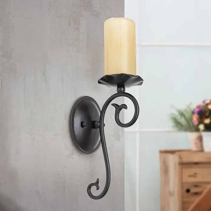 Orion Leuchten Wandleuchte - 40 W, L x B x H: 14 x 12,5 x 37 cm, E14 - Dunkle bronzefarbene Wandleuchte mit Schnörkelmuster und hellbeigem zylindrischem Schirm, an einer strukturierten Wand montiert.
