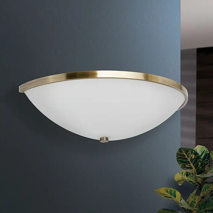 Orion Leuchten Wandleuchte - 40 W, L x B x H: 16 x 31 x 9 cm, E14 - Halbmond-Wandleuchte aus Messing und Milchglas an einer dunklen Wand.