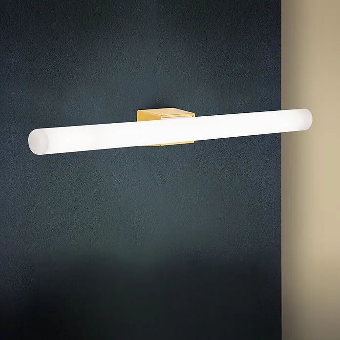 Orion Leuchten Wandleuchte - 60 W, L x B x H: 7 x 50 x 3,8 cm, S14d - Moderne lineare LED-Wandleuchte mit goldfarbenem Sockel und langem, mattweißem Röhrendiffusor, an dunkler Wand montiert.