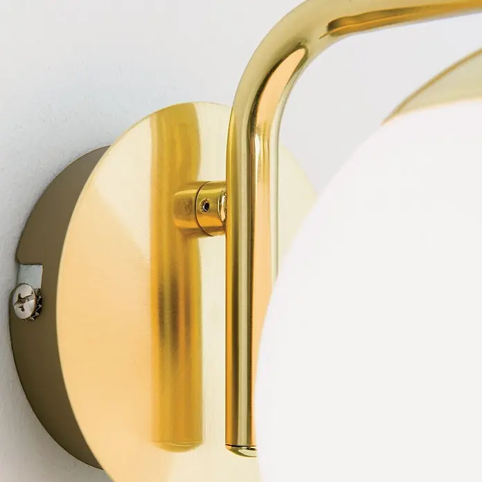 Orion Leuchten Wandleuchte - 40 W, L x B x H: 21 x 15 x 17 cm, E14 - Nahaufnahme einer goldfarbenen Wandleuchte mit geschwungenem Arm und kugelförmigem weißen Glasschirm.