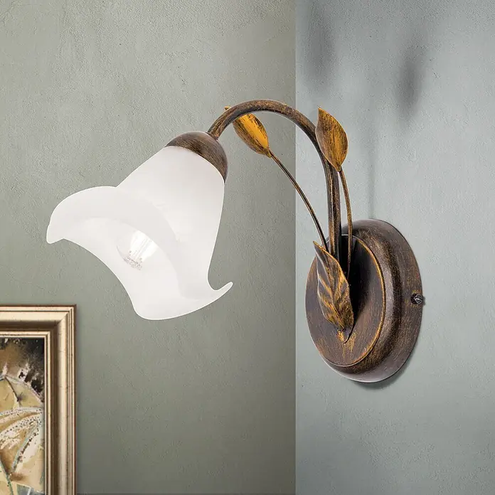 Orion Leuchten Wandleuchte - 40 W, L x B x H: 26 x 14 x 22,5 cm, E14 - Eine Wandleuchte aus Antikbronze mit weißem, blütenförmigem Glasschirm und dekorativen Metallblättern an der Wand.