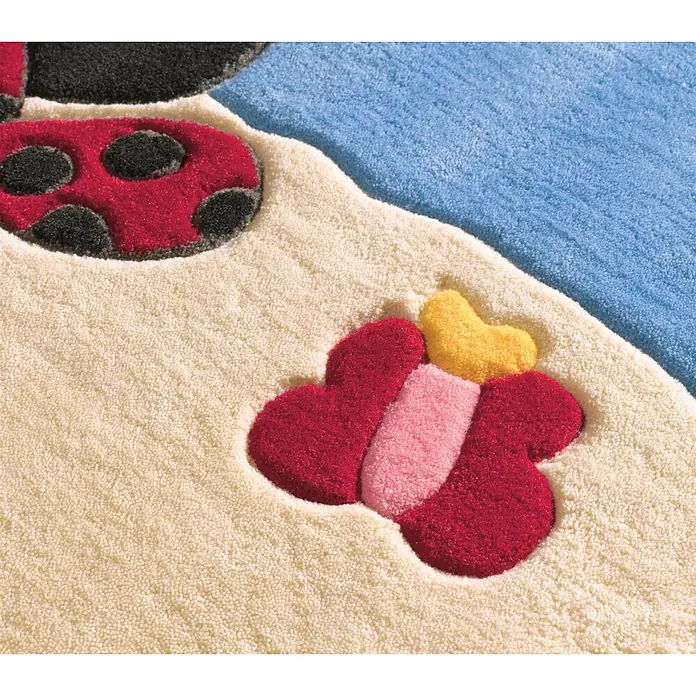 Kayoom Kinderteppich Joy 4091 - Multi, 160 x 110 cm, 100 % Modacryl - Nahaufnahme eines weichen, texturierten Teppichs mit rotem Marienkäfer und bunter Blume auf beigem und blauem Hintergrund.