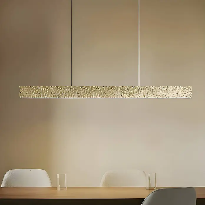 Lucande Pendelleuchte Nivara - messing / gold, gold, Schwarz - Goldene lineare Pendelleuchte mit strukturierter Oberfläche, über einem Esstisch hängend.
