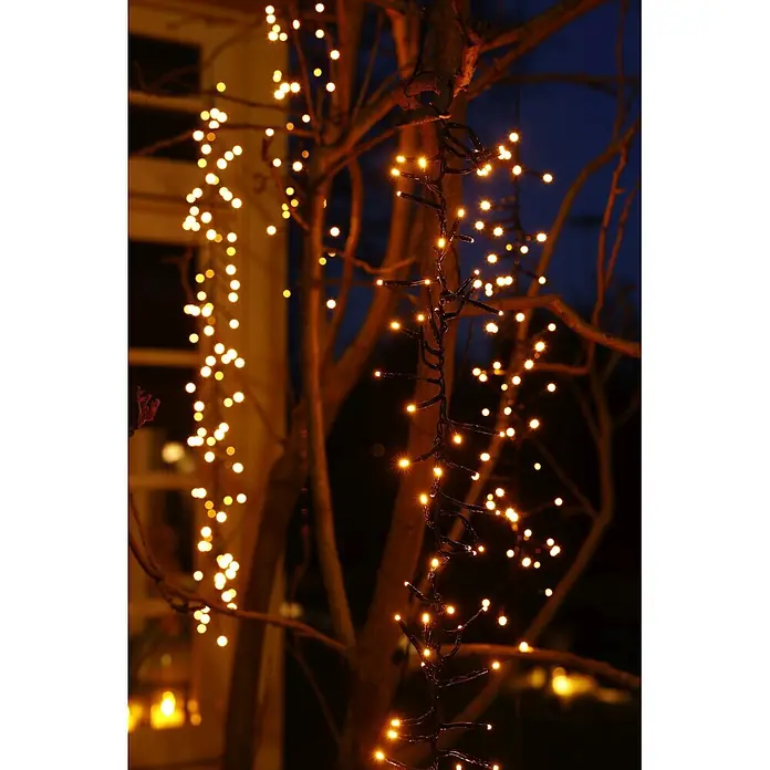 Lumineo Cascada de luz LED para árbol - Para exterior, 2 m, Blanco cálido, 480 ud., Funcionamiento en red - Guirnalda de luces blanco cálido con cables oscuros ilumina ramas de árboles por la noche, creando un brillo festivo.