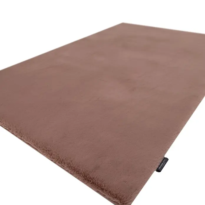 Kayoom Fellteppich Boundless 225 - Puderrosa, 170 x 120 cm, 90 % Polyester, 10 % Baumwolle - Eine rechteckige, weiche, flauschige, gedämpft braune Kunstfellmatte oder Teppich, mit einem schwarzen Markenetikett am Rand.