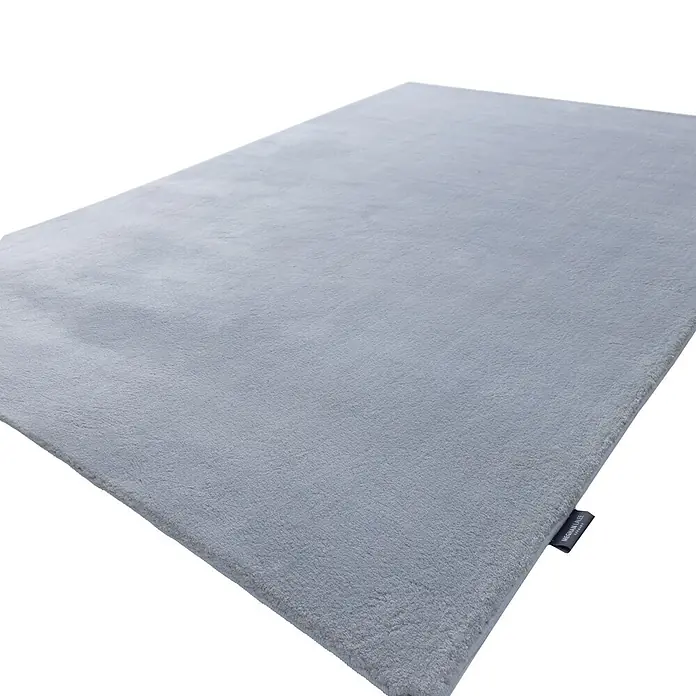 Kayoom Fellteppich Boundless 225 - Grau, 170 x 120 cm, 90 % Polyester, 10 % Baumwolle - Hellgrauer, weicher Teppich mit feiner Textur und sichtbarem Markenetikett an einer Ecke.