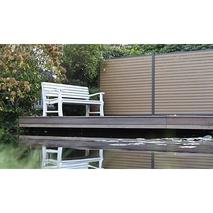 GartenLand Steckzaun-Element WPC Zaun Stockholm Musterstück - B x H: 20 x 7,5 cm, Karamellbraun, Verbundwerkstoff - Weiße Gartenbank auf Holzdeck an Sichtschutzzaun, mit Blick auf Teich.