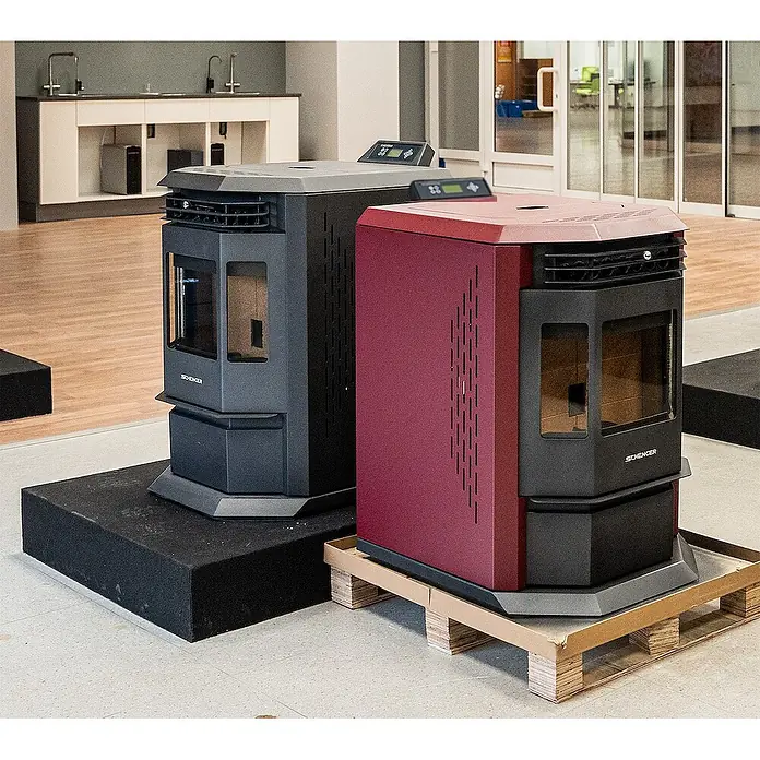 SCHENGER Pelletofen HLP3602 - 9,3 kW, Raumheizvermögen: 200 m³, 0,9 kg/h, Farbe Verkleidung: Rot - Zwei moderne Pelletofen, einer dunkelgrau, einer bordeauxrot, mit Sichtfenstern und Bedienfeldern, in einem Ausstellungsraum präsentiert.
