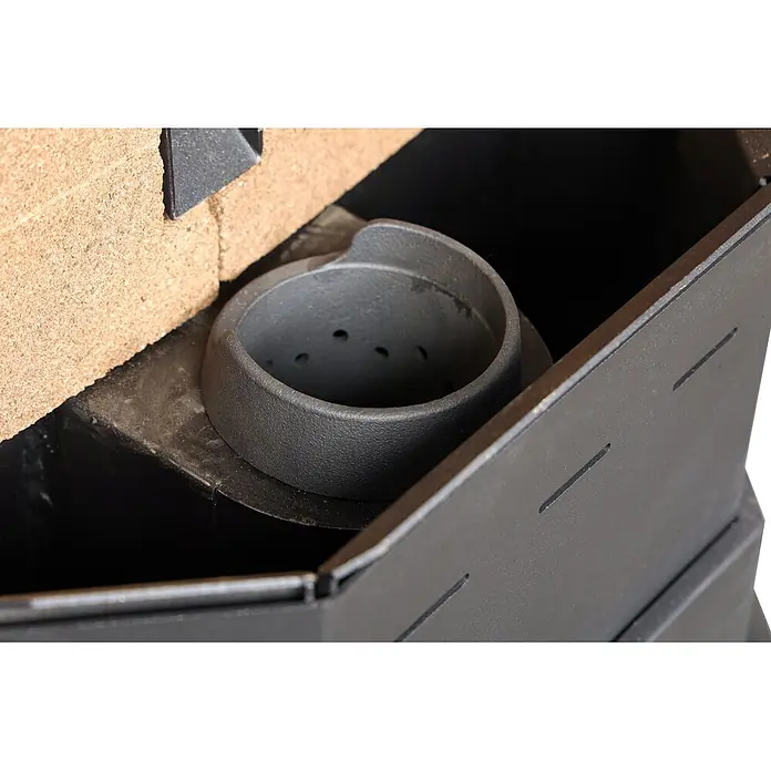 SCHENGER Pelletofen HLP3602 - 9,3 kW, Raumheizvermögen: 200 m³, 0,9 kg/h, Farbe Verkleidung: Schwarz - Nahaufnahme eines dunkelgrauen, strukturierten Metallbrenners oder Rosts mit Löchern, in einem mit hellbraunen Schamottsteinen ausgekleideten Ofen.