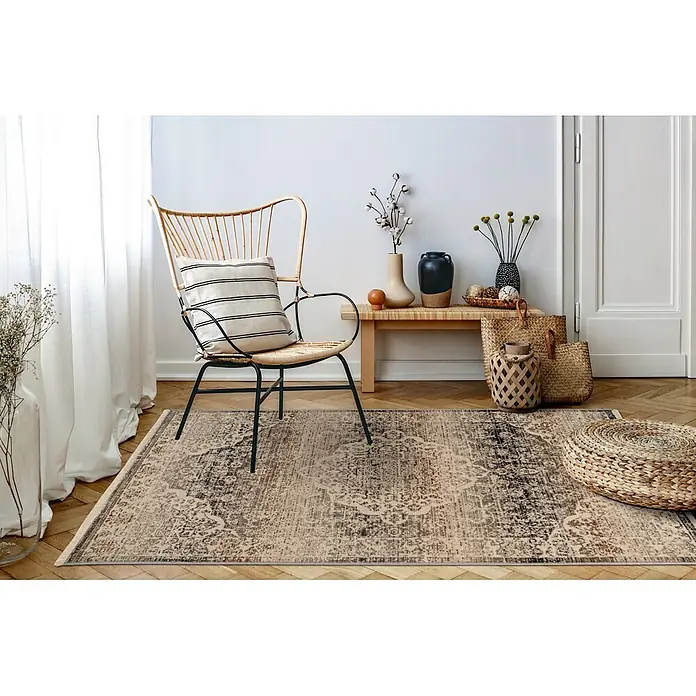 Kayoom Kurzflorteppich Charin 725 - Beige, 180 x 120 cm, 100 % Polypropylen - Ein gemusterter Vintage-Teppich in Beige-, Braun- und Schwarztönen auf einem Holzboden in einem gemütlichen Raum.