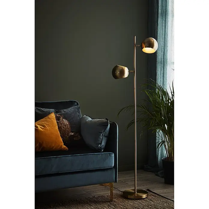 Markslöjd Stehleuchte Edgar - 40 W, Höhe: 145 cm, Antik, E14 - Goldene Stehlampe mit zwei Leuchten, beleuchtet ein dunkelblaues Sofa in einem Wohnzimmer.