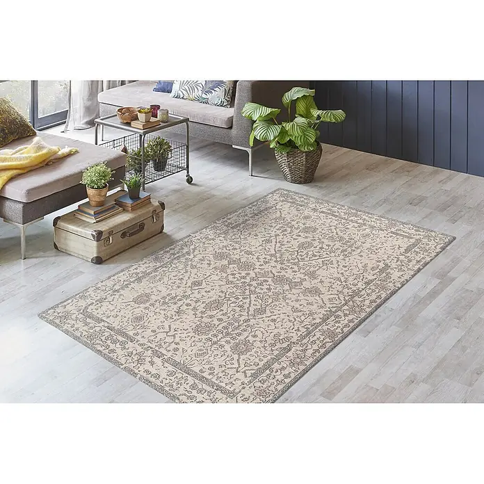 Kayoom Flachgewebeteppich Perry 125 - Creme, 170 x 120 cm, 75 % Baumwolle, 25 % Polyester - Heller beiger Teppich mit zarten Blumenmustern auf hellem Holzboden in einem Wohnzimmer.