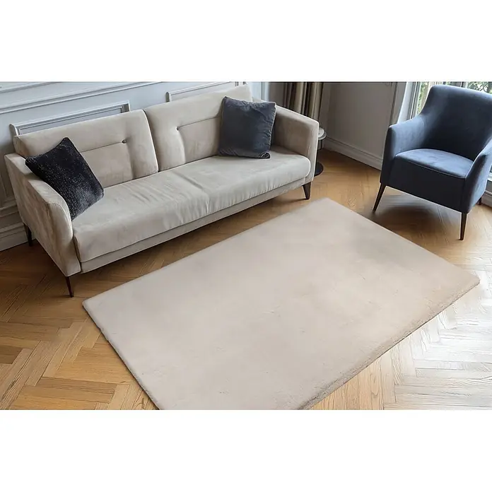 Kayoom Fellteppich Summit 625 - Taupe, 170 x 120 cm, 90 % Polyester, 10 % Baumwolle - Heller, rechteckiger Teppich in Beige auf Holzfußboden im Wohnzimmer vor einem Sofa.