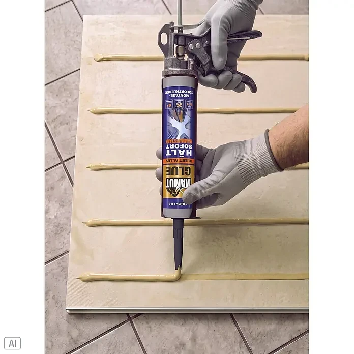Wandpaneel - 260 x 90 cm, Marble Lombard, Stone Polymer Composite (SPC) - Hände in grauen Handschuhen bedienen eine Kartuschenpistole, die beigen Bostik Mammut Kleber auf ein helles Paneel aufträgt.