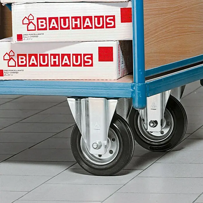 Stabilit Rueda de transporte industrial - Diámetro ruedas: 100 mm, Capacidad de carga: 200 kg, Casquillo liso, Con placa - Primer plano de un carro con cajas etiquetadas como "BAUHAUS", sobre un suelo alicatado.