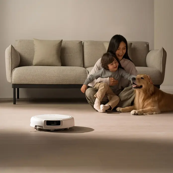 DJI Saugwischroboter S - Saugkraft: 25.000 Pa, Akkulaufzeit: 180 min, Fassungsvermögen Roboter: 260 ml - Weißer Saugroboter auf hellem Boden in einem Zuhause, mit einer Familie und Hund in der Nähe.