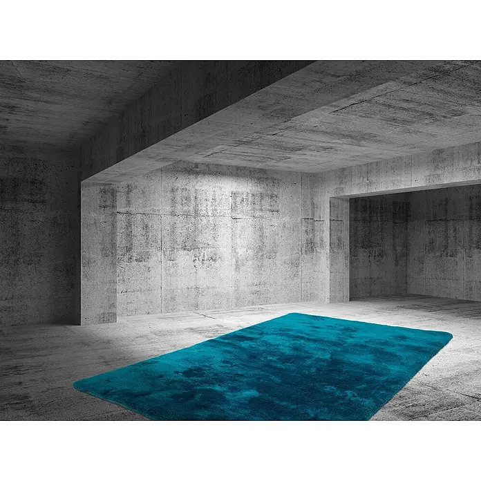 Kayoom Hochflorteppich Dolphin 500 - Blau, 290 x 200 cm, 100 % Polyester - Flauschiger, leuchtend türkiser Teppich auf einem Betonboden in einem Raum im Industriestil.