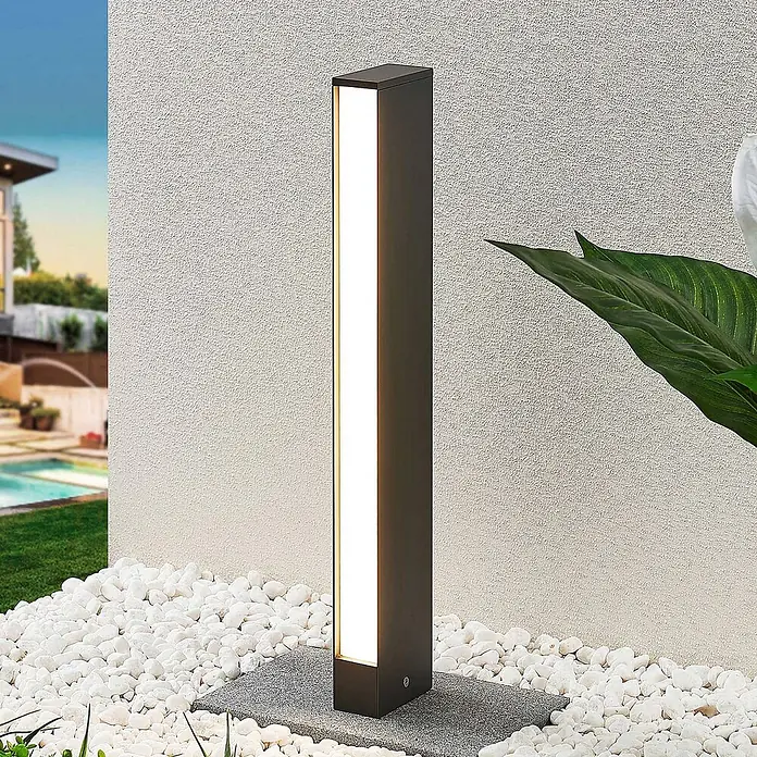 Lucande LED Wegeleuchte Pollerleuchte dunkelgrau 60 cm, Gartenlampe -  - Anthrazitfarbene rechteckige LED-Pollerleuchte für den Außenbereich, in einem Garten mit Kiesbeet.