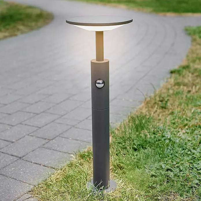 Lucande LED Wegeleuchte mit Bewegungsmelder Gartenleuchten mit Strom 60 cm -  - Dunkelgraue Wegeleuchte mit Bewegungssensor, beleuchtet, neben einem gepflasterten Weg.