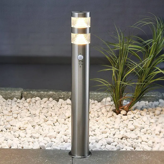 Lindby Edelstahl LED Wegeleuchte / Pollerleuchte 60 cm mit Bewegungsmelder -  - Gebürstete Edelstahl-Bollard-Außenleuchte mit zwei Leuchtsektionen und integriertem Bewegungssensor, zwischen weißen Kieselsteinen.