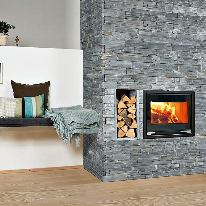 Aduro Kaminofeneinsatz 5-1 - L x B x H: 46 x 63,5 x 57,4 cm, Schwarz - Das Bild zeigt einen modernen Kamin mit einer Verkleidung aus grauen Natursteinen und einem integrierten Holzregal.