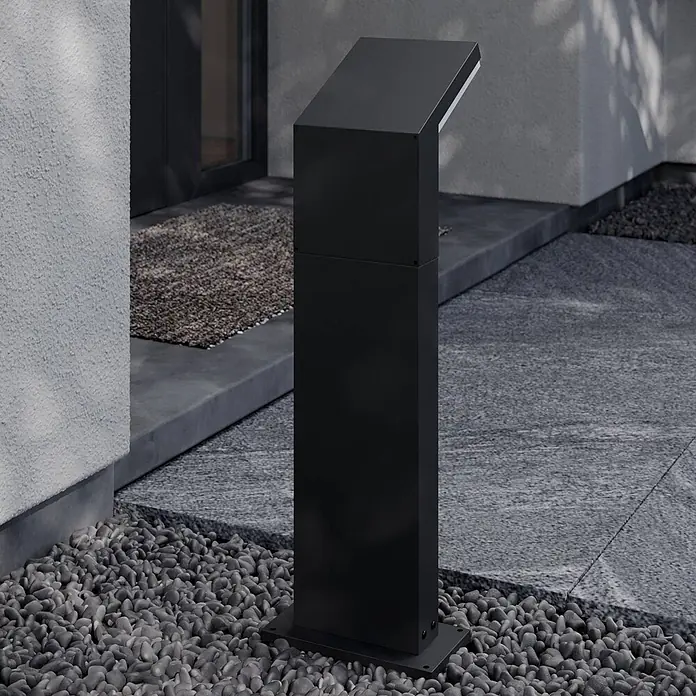 Arcchio LED Wegeleuchte in dunkelgrau, weiß, Gartenlampe -  - Schwarze, moderne Außenleuchte auf grauem Kies vor einem Gebäudeeingang.