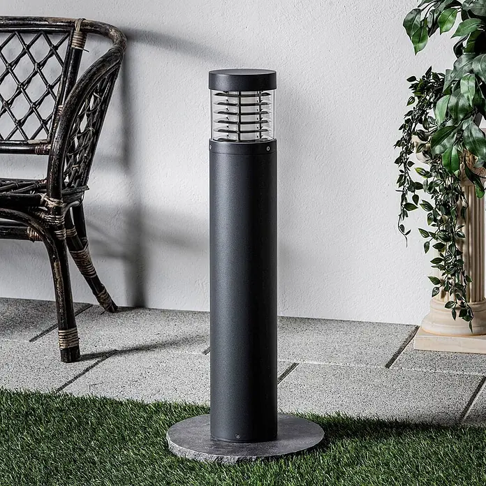 Lucande LED Wegeleuchte / Pollerleuchte 65cm, inkl. 15W LED -  - Dunkelgraue Außenpollerleuchte mit Lamellenaufsatz, auf Steinbasis zwischen Gras und Pflastersteinen stehend.