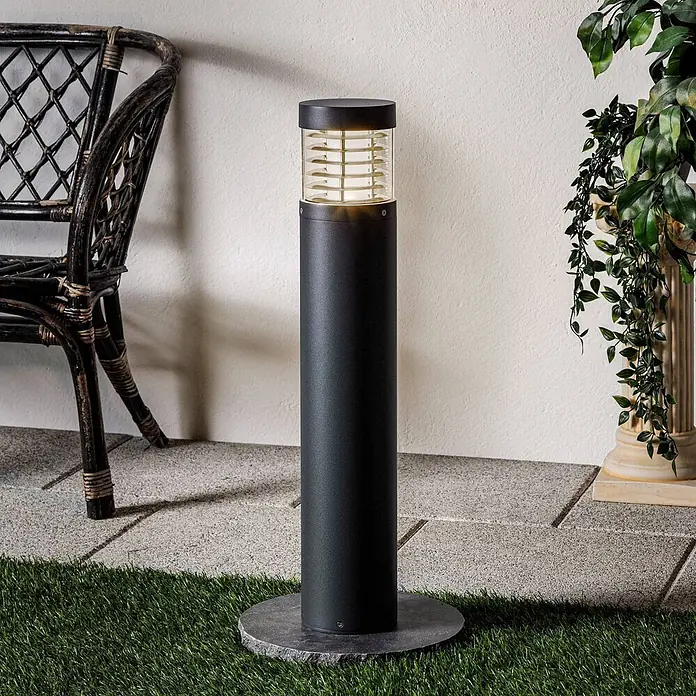Lucande LED Wegeleuchte / Pollerleuchte 65cm, inkl. 15W LED -  - Schwarz zylindrische Außenleuchte mit transparentem Oberteil auf rundem Steinsockel zwischen Pflastersteinen und Kunstrasen.