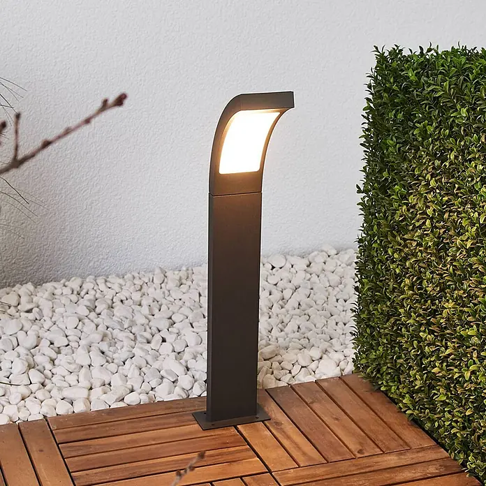 Lucande LED Wegeleuchte anthrazit Sockelleuchte 60 cm Gartenlampe Aluminium -  - Dunkle Wegeleuchte spendet warmes Licht, auf Holzterrasse neben weißen Kieseln im Garten installiert.