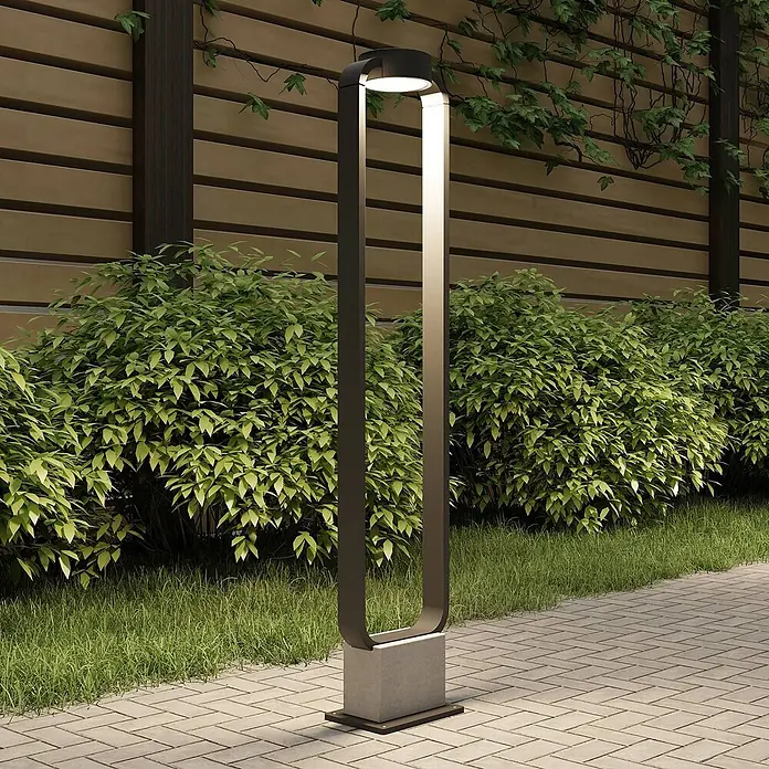 Lucande Außenlaterne Belna -  - Moderne dunkelgraue U-förmige Außenpollerleuchte mit integrierter LED auf hellem Betonsockel an einem gepflasterten Weg.