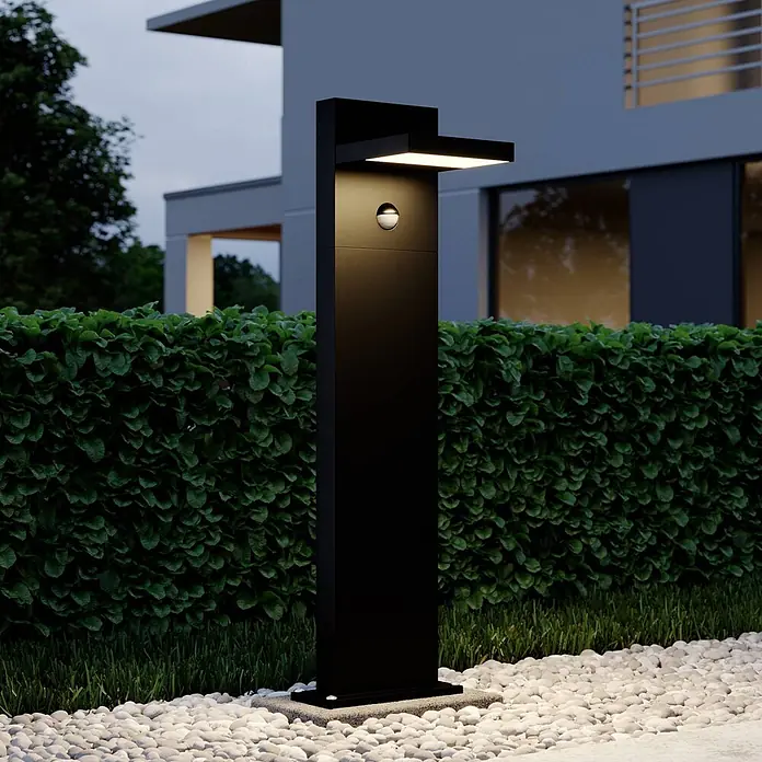Lucande Außenlaterne Silvan -  - Schwarze Außenpollerleuchte mit Abwärts- und Aufwärtsbeleuchtung, integriertem Bewegungssensor, in einem modernen Garten.