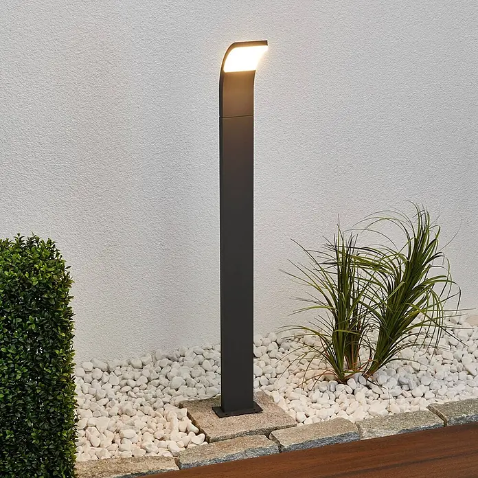 Lucande Außenlaterne Timm -  - Moderne anthrazitfarbene LED-Wegeleuchte, die einen Gartenweg mit Kies und Pflanzen beleuchtet.