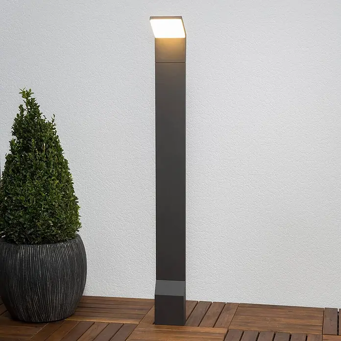Lucande LED Wegeleuchte anthrazit Gartenlampe 100cm Pollerleuchte Aluminium -  - Anthrazitfarbene LED-Wegeleuchte auf einer Holzterrasse, neben einer grünen Topfpflanze.