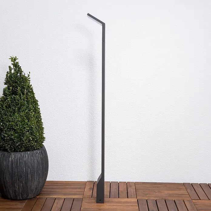 Lucande LED Wegeleuchte anthrazit Gartenlampe 100cm Pollerleuchte Aluminium -  - Moderne dunkelgraue Outdoor-Stehlampe mit angewinkeltem Kopf, auf Holzterrasse neben einer Pflanze.