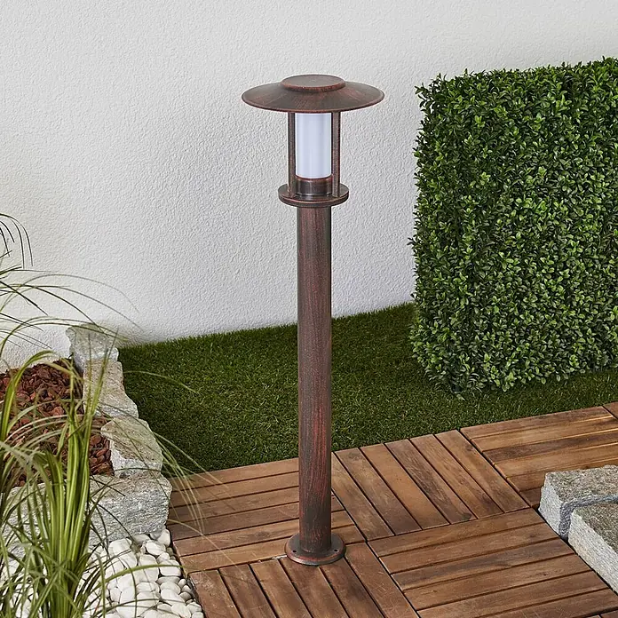 Lindby LED Wegeleuchte in rost, transparent, Gartenlampe -  - Bronze-farbene Gartenwegleuchte mit weißem Diffusor auf Holzterrassenboden in Gartenumgebung.