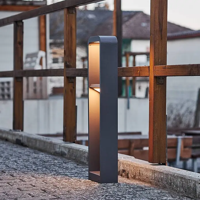 Lindby Außenlaterne Darko -  - Dunkelgraue Wegeleuchte mit warmer LED-Beleuchtung auf einem gepflasterten Weg.