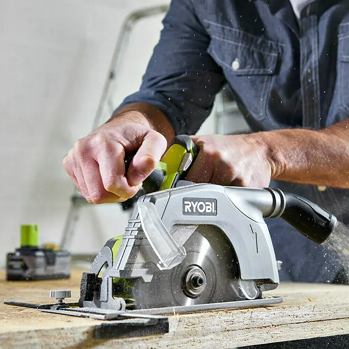 Ryobi ONE+ Maschinenpaket - Akku-Handkreissäge R18CS-0 + gratis Starter-Kit - Eine Ryobi Kreissäge in Aktion, bedient von einem Mann, während sie durch Holz schneidet, ideal für Heimwerkerprojekte.