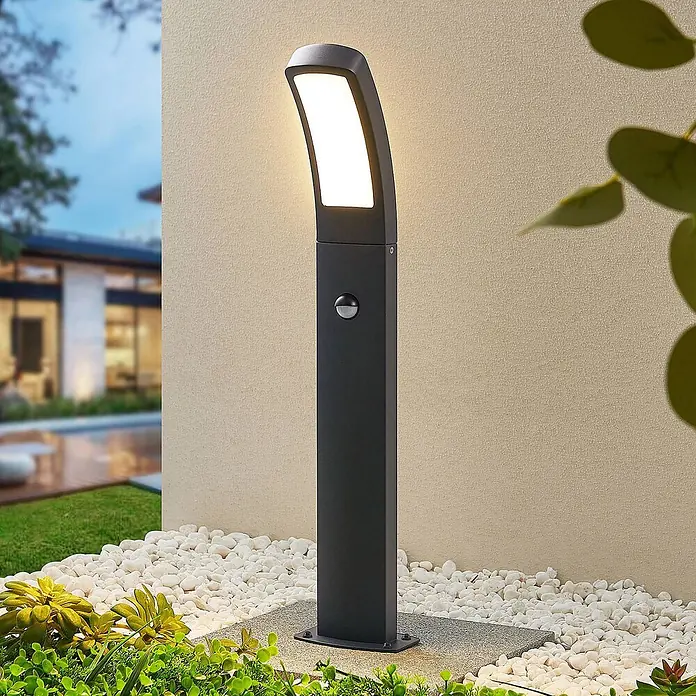 Lindby Außenlaterne Moshe -  - Moderne schwarze Außenwegleuchte mit beleuchtetem LED-Panel und Bewegungssensor im Garten.