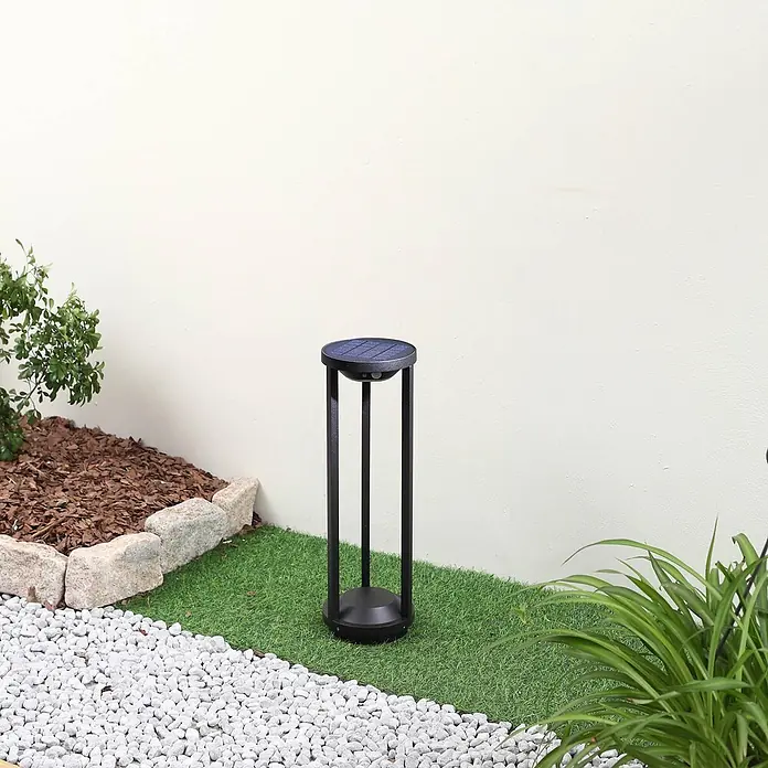 Lucande Außenlaterne Nilea -  - Schwarze solarbetriebene Außenlampe in einem Garten auf Kunstrasen und weißen Kieselsteinen.